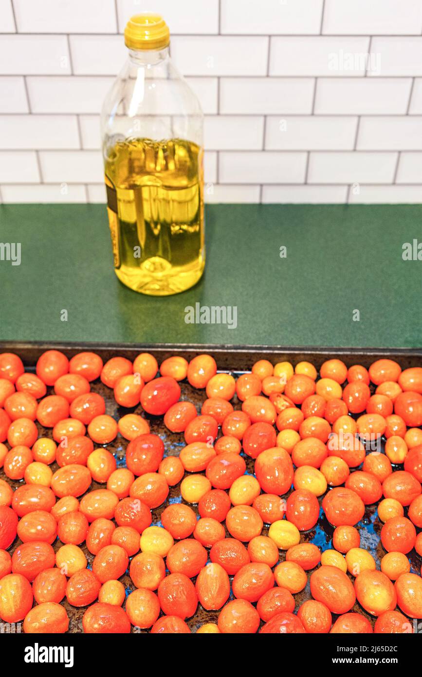 Tomates de uva de invierno asados en una fuente para cocinar salsa de tomate fresco. Alimentación saludable dieta mediterránea. Foto de stock