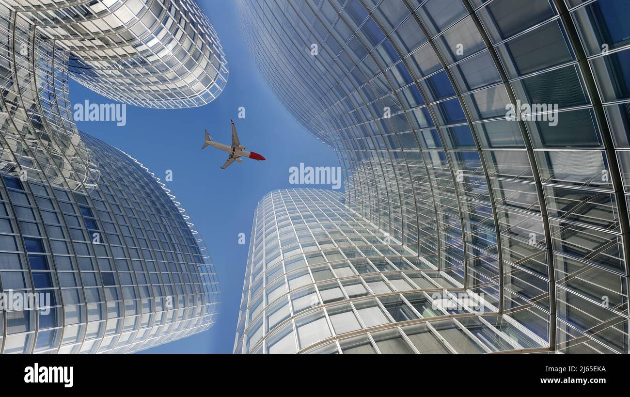 Avión volando sobre modernos rascacielos de vidrio de oficina Foto de stock