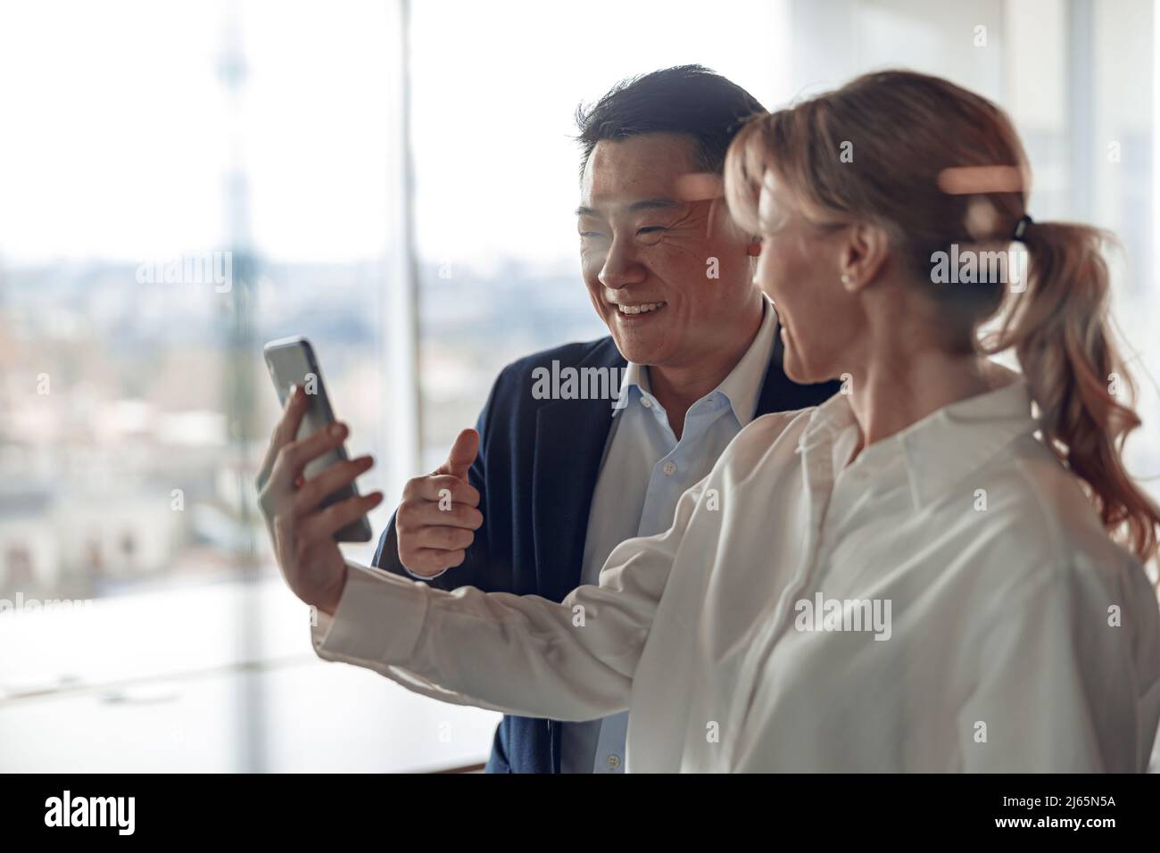 una mujer de negocios madura se muestra a su pareja abandonada pantalla de smartphone en la oficina moderna Foto de stock