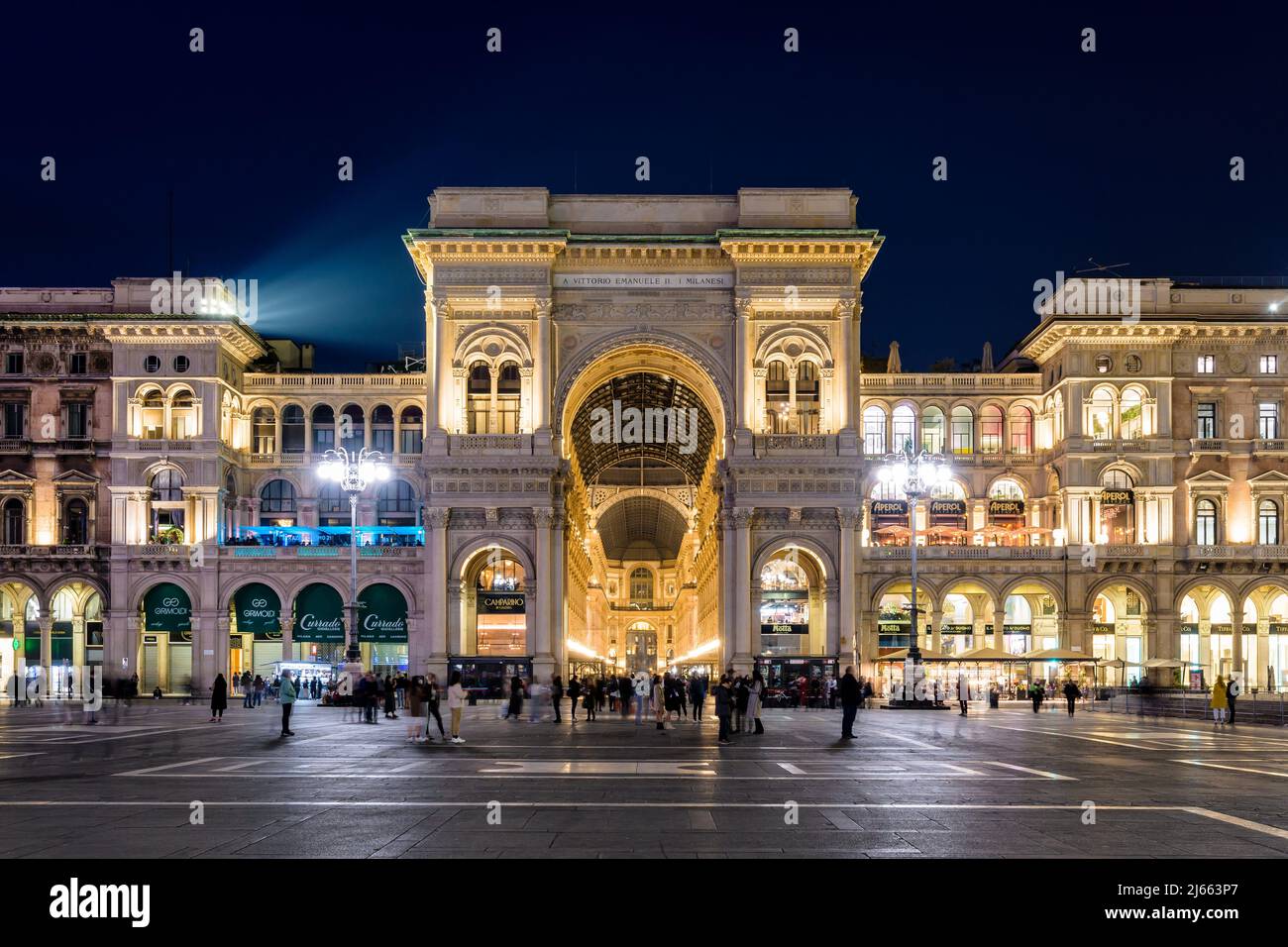 Vista frontal de la entrada del arco triunfal de la Galería Vittorio Emanuele II, centro comercial acristalado en la Piazza del Duomo por la noche en Milán, Italia Foto de stock