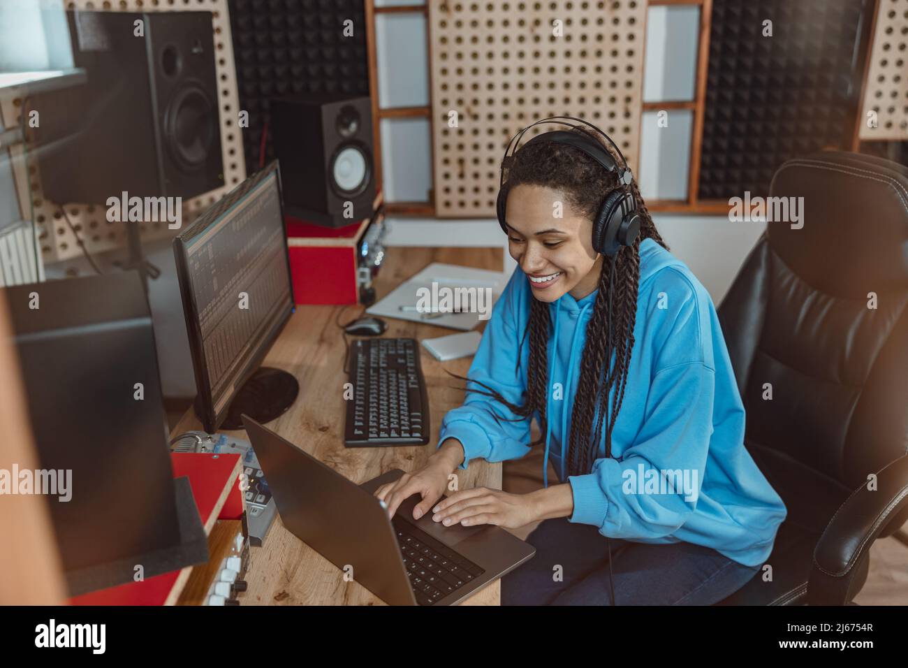 Alegre ingeniero de sonido afroamericano trabajando en un portátil en el estudio de grabación de sonido Foto de stock