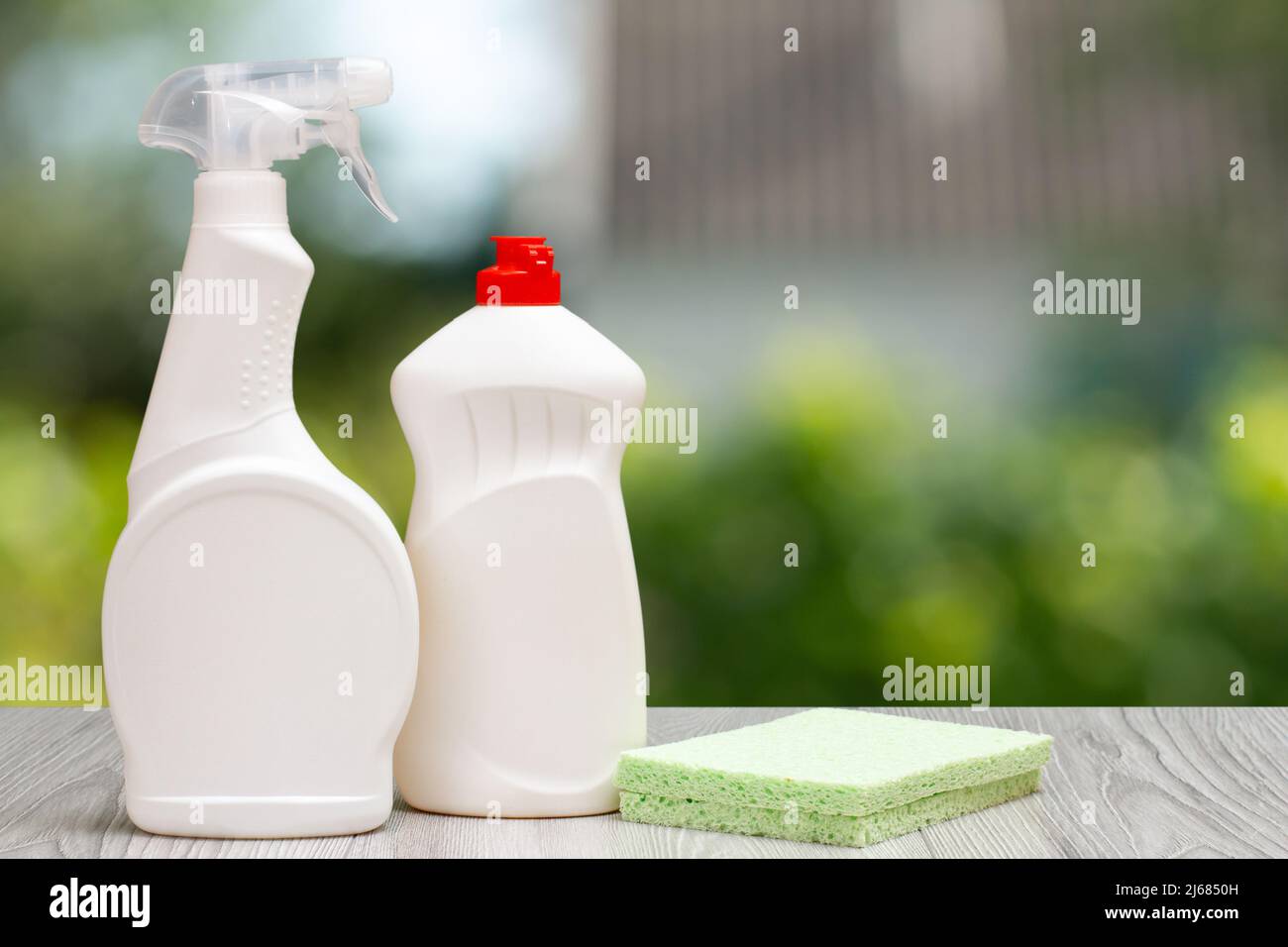 https://c8.alamy.com/compes/2j6850h/botellas-de-plastico-de-liquido-lavavajillas-limpiador-de-vidrio-y-azulejos-con-esponja-sobre-el-fondo-borroso-concepto-de-lavado-y-limpieza-2j6850h.jpg