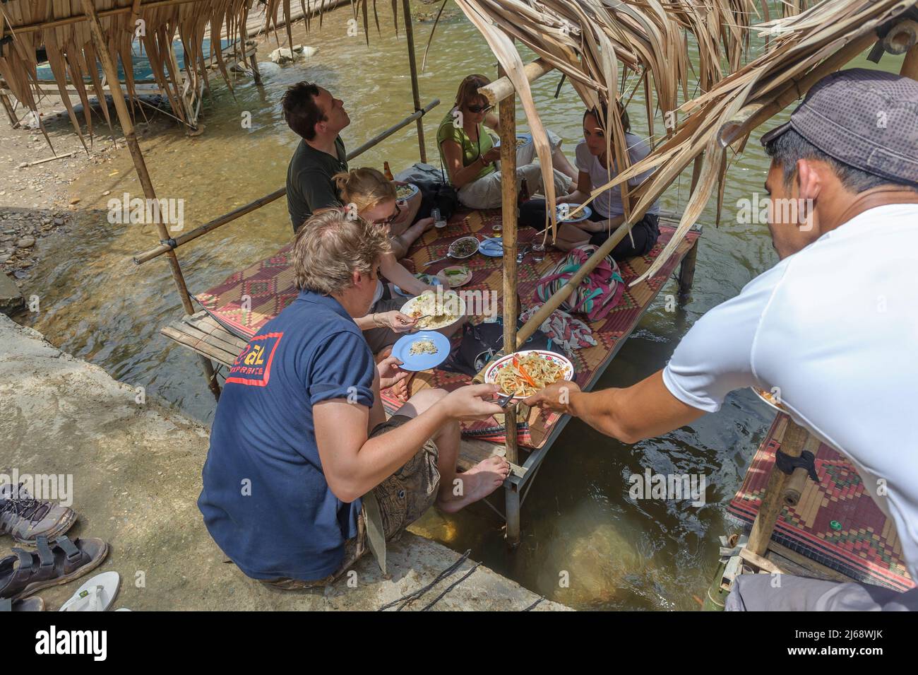 Los turistas disfrutan de un almuerzo tradicional en una cabaña restaurante junto al río, Nong Lu, distrito de sangkhla buri, Tailandia Foto de stock