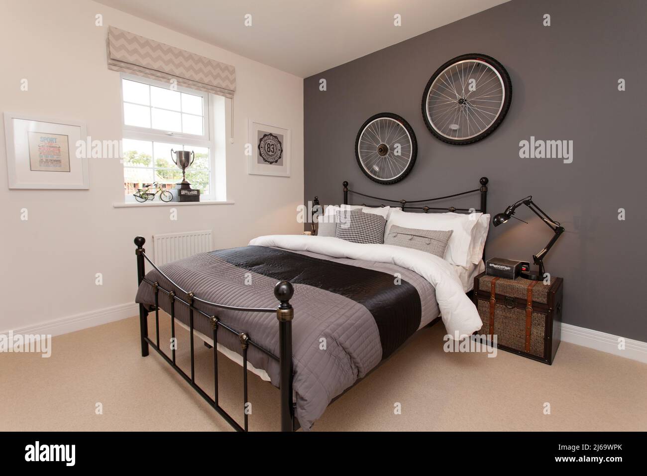 Dormitorio temático de ciclismo, ruedas de bicicleta en la pared, cama de hierro, Foto de stock