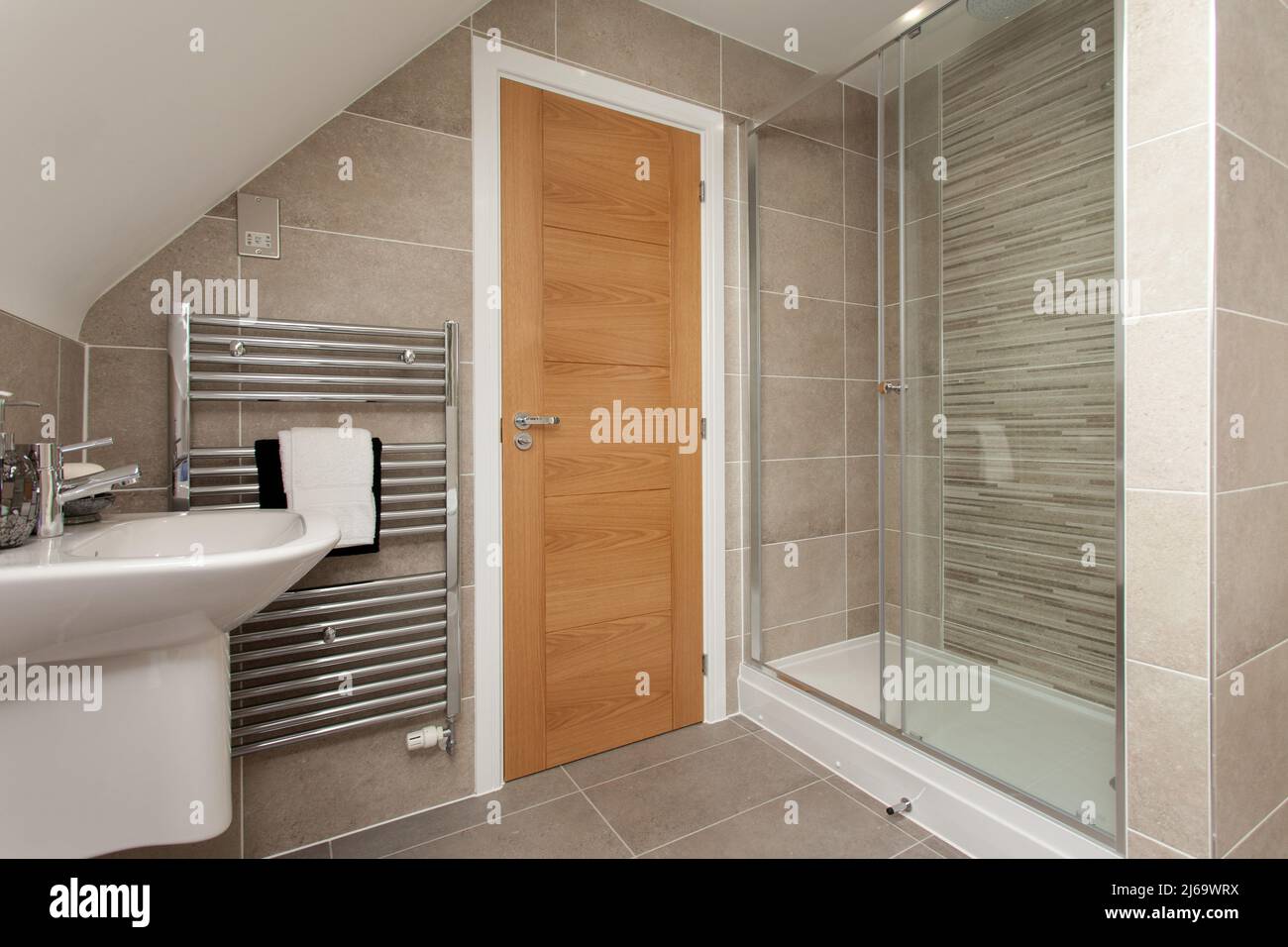 Moderno baño con azulejos, lavabo con ducha en colores neutros. Foto de stock