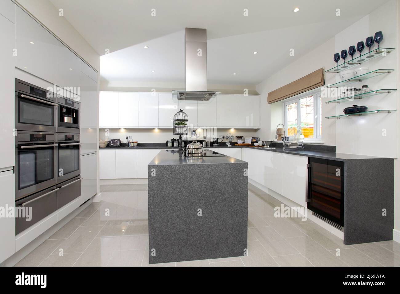 Cocina en casa de nueva construcción, isla central y encimeras de granito gris compuesto de cuarzo, ultra moderno. Foto de stock