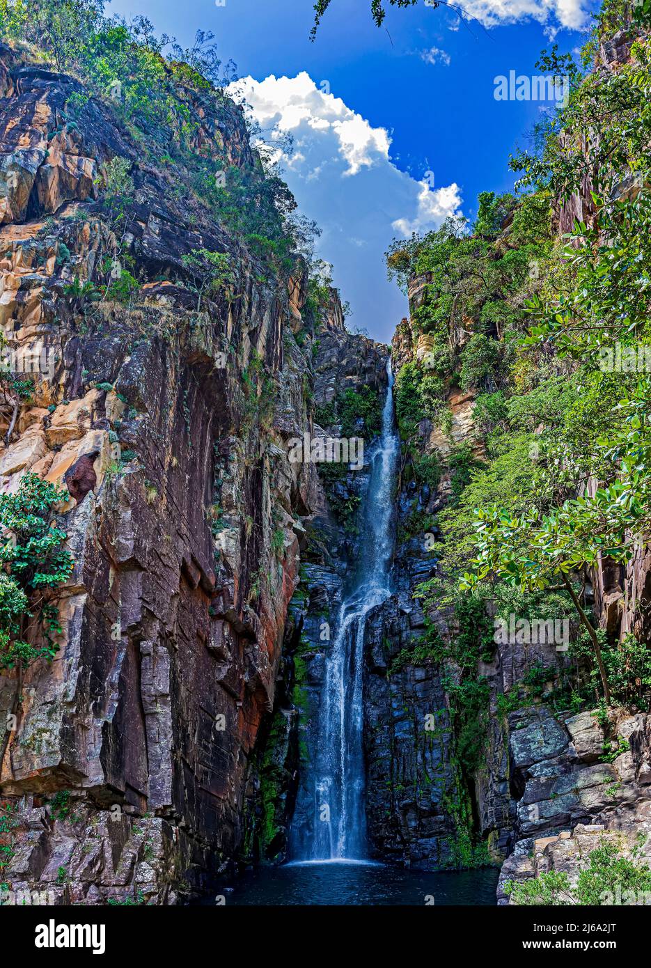 Cascada de Veu da Noiva (Velo de la Novia) entre las rocas y la vegetación típica del Cerrado en Serra do CIPO en el estado de Minas Gerais, B Foto de stock