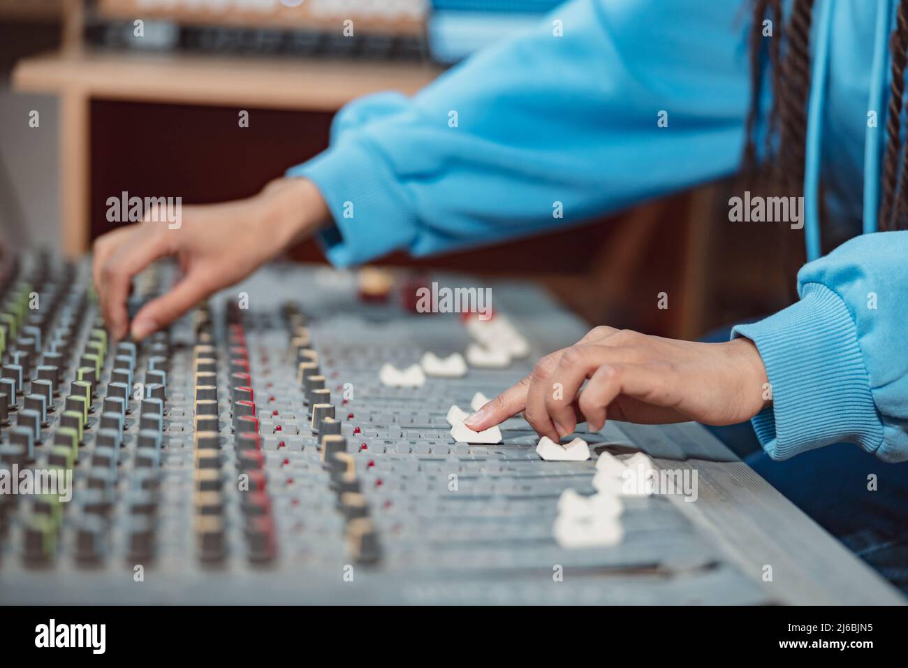 Ingeniero de sonido femenino, productor de músico manos usando tablero de mezcla y software para crear canción en estudio de grabación Foto de stock