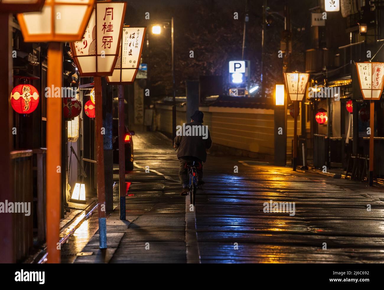 Paseos en bicicleta en la calle oscura y vacía después de la lluvia en el histórico distrito japonés Foto de stock