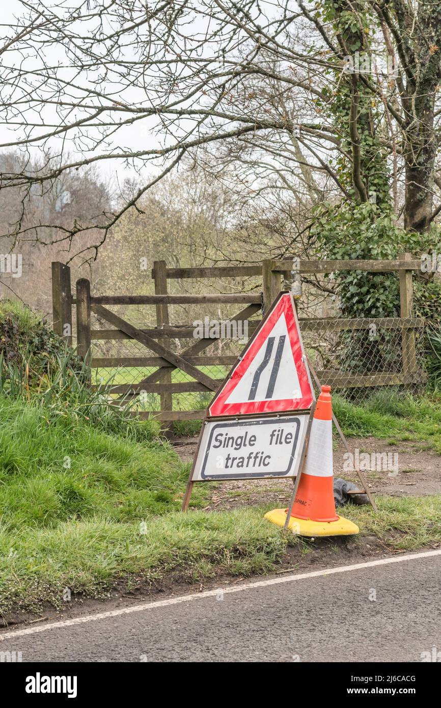Cono de carretera naranja y blanco y señal de advertencia de tráfico de un solo archivo en una carretera nacional del Reino Unido en la que se están realizando obras viales, Foto de stock
