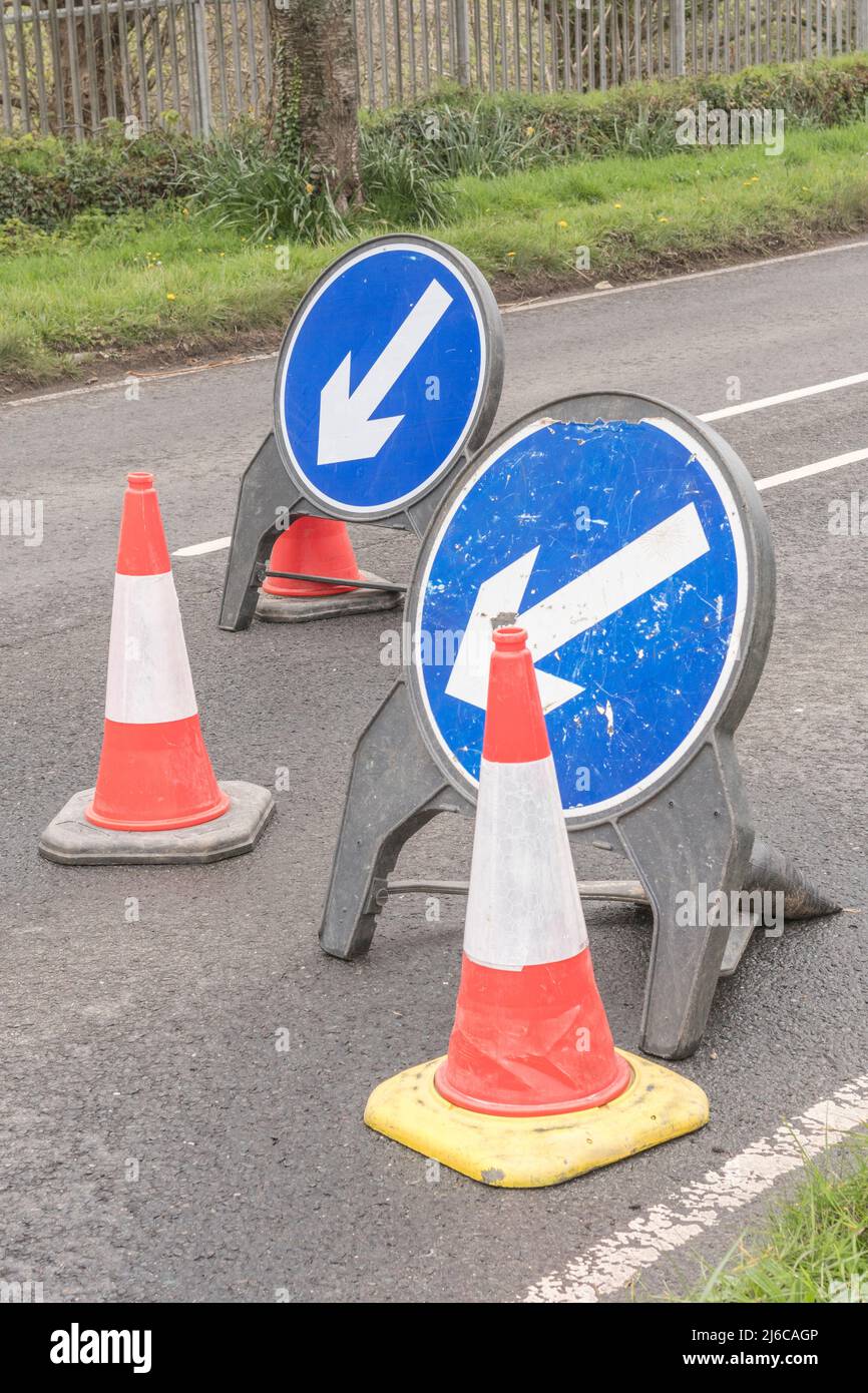 Siga las señales azules de la izquierda en el Reino Unido, como parte de la señalización de obras en una carretera de Cornwall. Para reparaciones o mantenimiento de carreteras, el tráfico se ralenti. Foto de stock