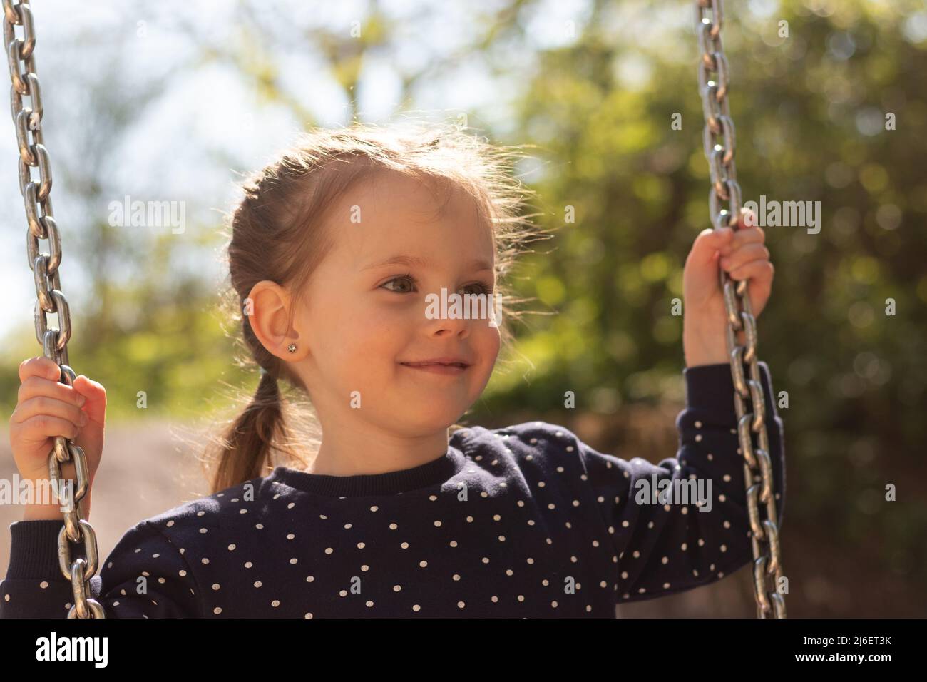 Pequeña chica linda con lechales sonrientes paseos en un columpio en ropa  de topos en el parque Fotografía de stock - Alamy