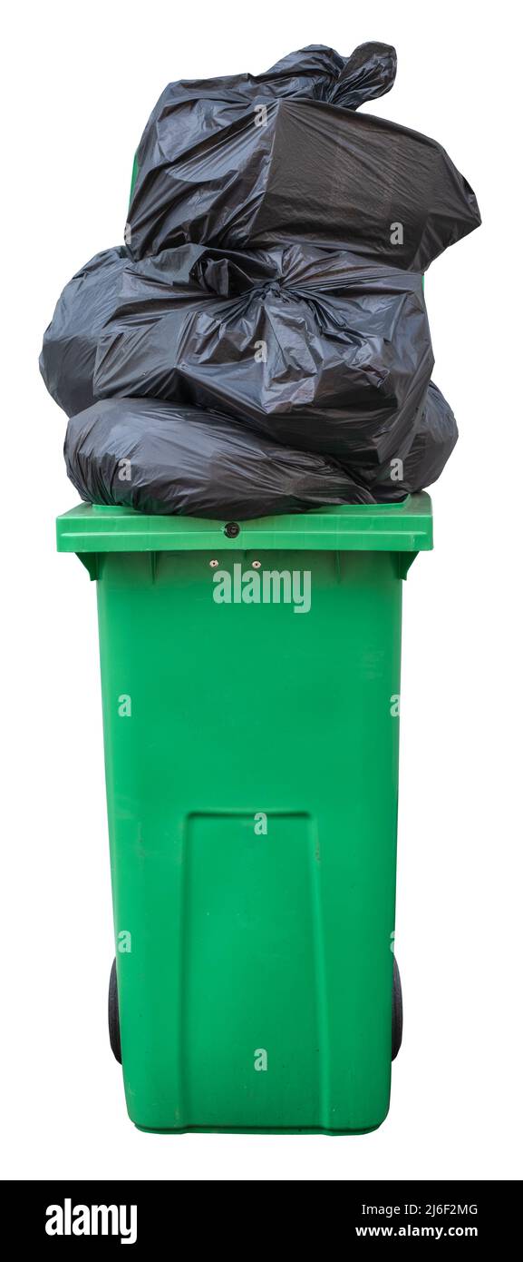 Una papelera verde de Wheelie, que se desborda con bolsas de basura (basura), aislada sobre un fondo blanco Foto de stock