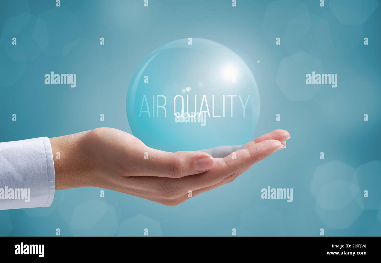 Mano sujetando una burbuja de aire limpio: Control del índice de calidad del aire Foto de stock