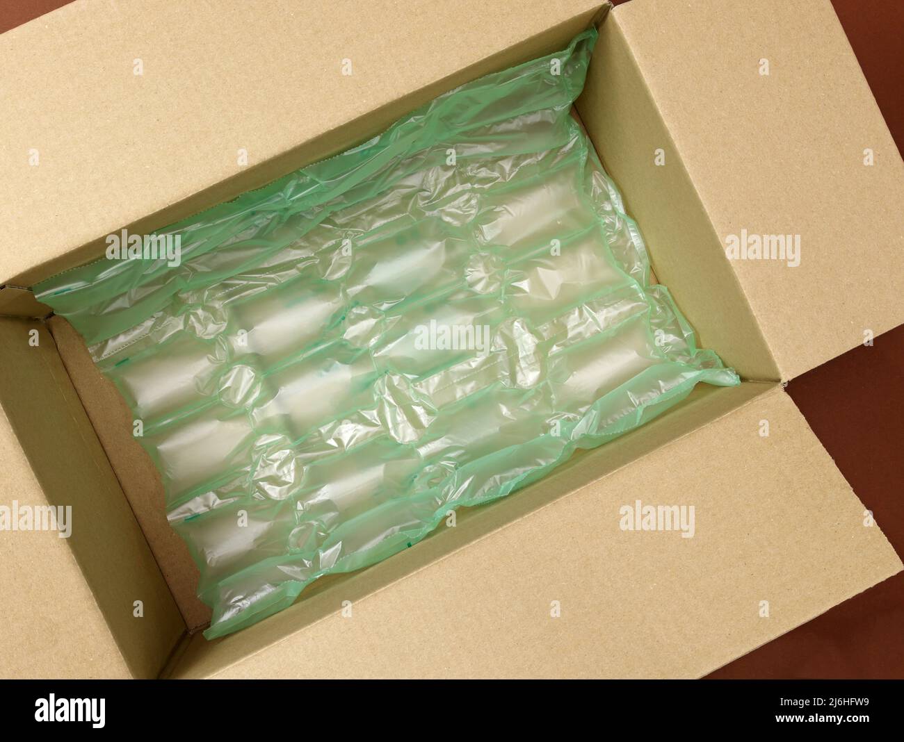 Polietileno Envolturas de burbujas verdes de aire en una vista superior de  caja de cartón marrón. Caja de entrega llena de plástico con envoltorio de  burbujas. Embalaje de productos para entrega, shi