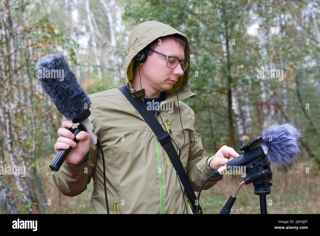 El tipo con micrófono y auriculares Shotgun Condenser está grabando los sonidos de la naturaleza. Grabación de sonidos ambientales Foto de stock