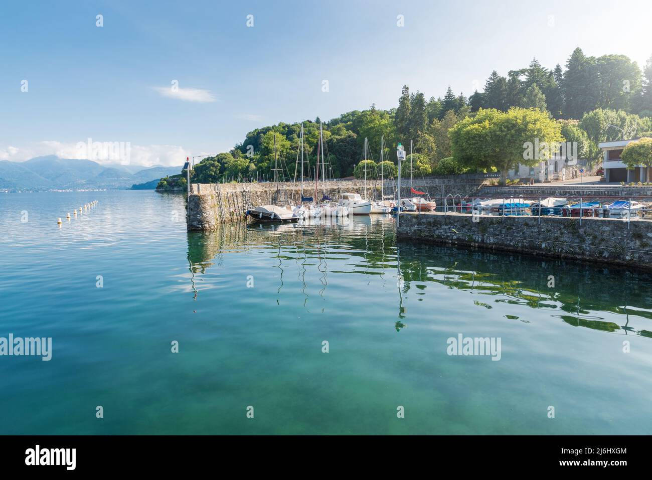 Pequeño puerto típico en un gran lago en el norte de Italia. Lago Maggiore a orillas del lago de la ciudad de Ispra con barcos amarrados. Paisaje veraniego Foto de stock
