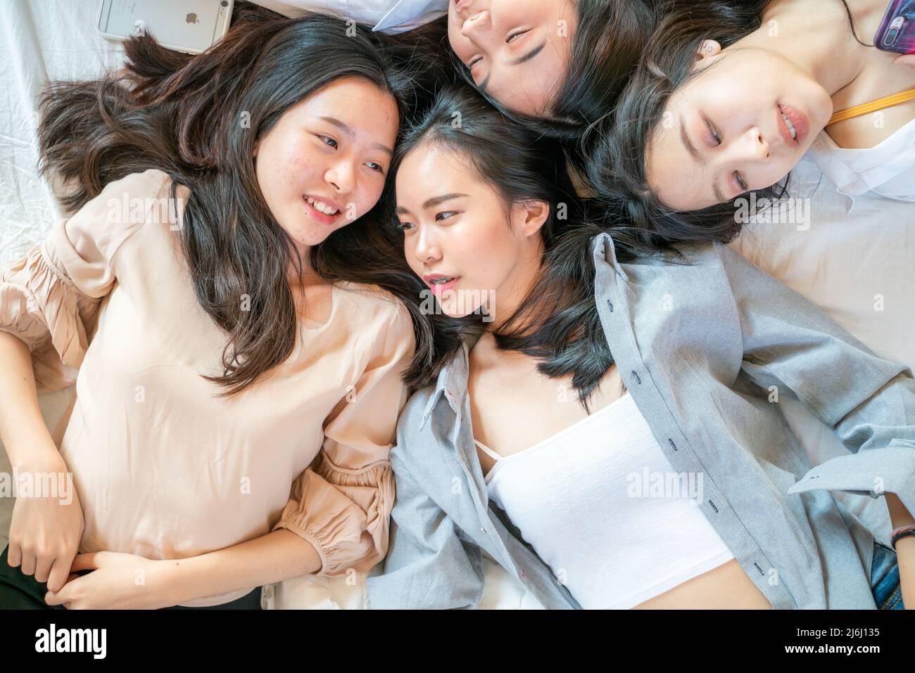 Vista superior autorretrato de un atractivo grupo de amigos chicas muy  bonitas tumbadas en una cama blanca hablando grito mirando a la cámara  Fotografía de stock - Alamy