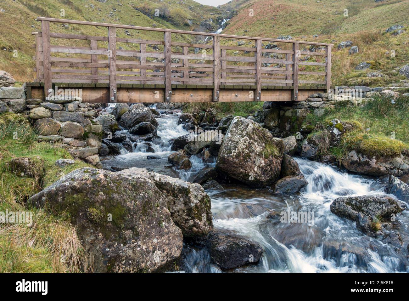 Puente peatonal de madera sobre el río Red Tarn Beck, un arroyo de montaña que se tambalea por debajo de Helvellyn, Glenridding, English Lake District, Cumbria, Reino Unido Foto de stock