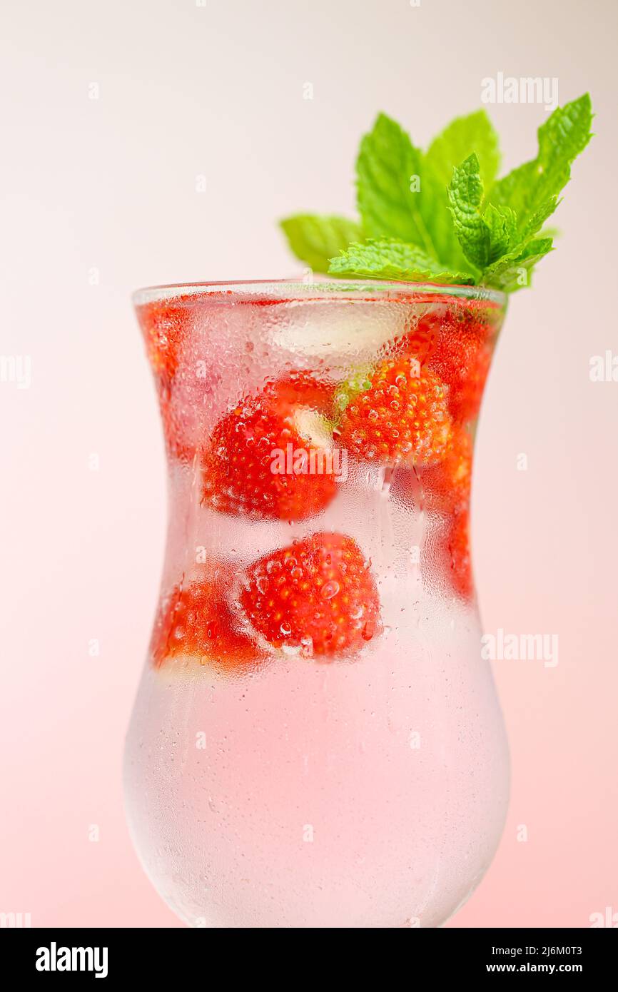 Bebida de fresa. Bebidas de verano. Cóctel refrescante. Agua en vaso con fresas. Agua mineral con hielo y fresas en una goblet de cristal y. Foto de stock