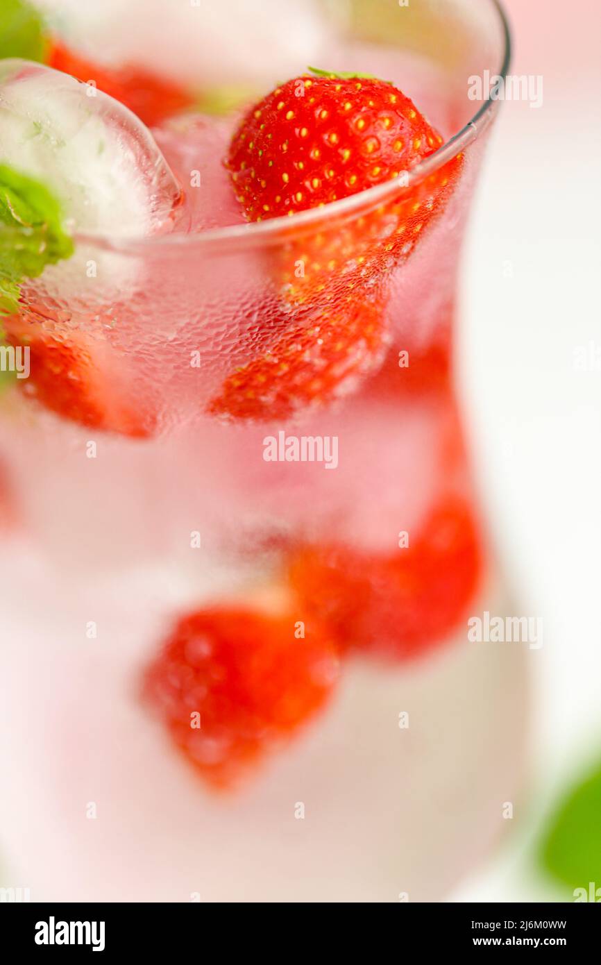 Bebida de fresa. Bebidas de verano. Cóctel refrescante. Agua con hielo y fresas. Agua mineral con hielo y fresas en una goblet de cristal y. Foto de stock