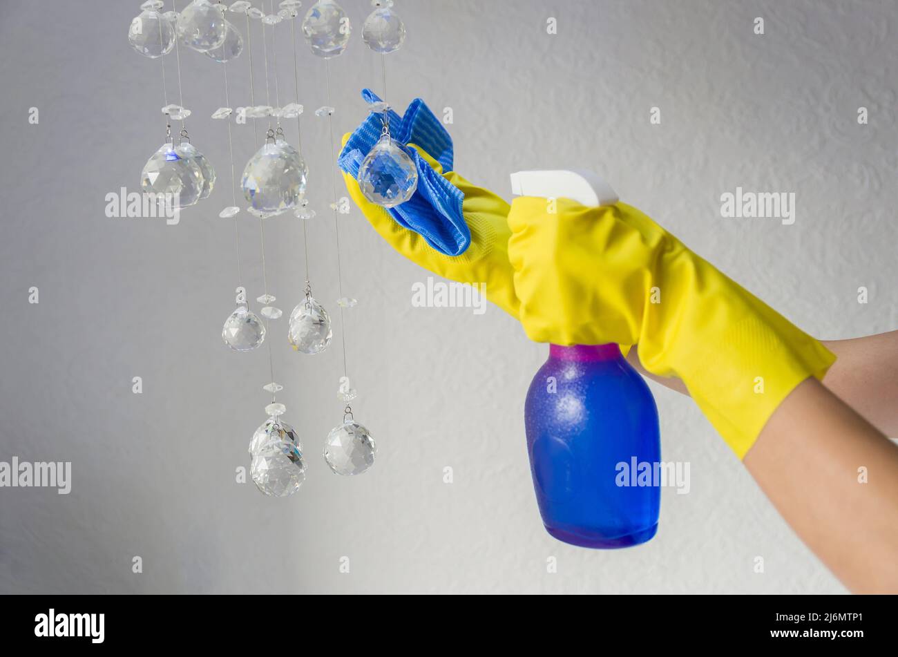 Gran concepto de limpieza doméstica, mano enguantada barrido araña de luces de cristales. Foto de stock
