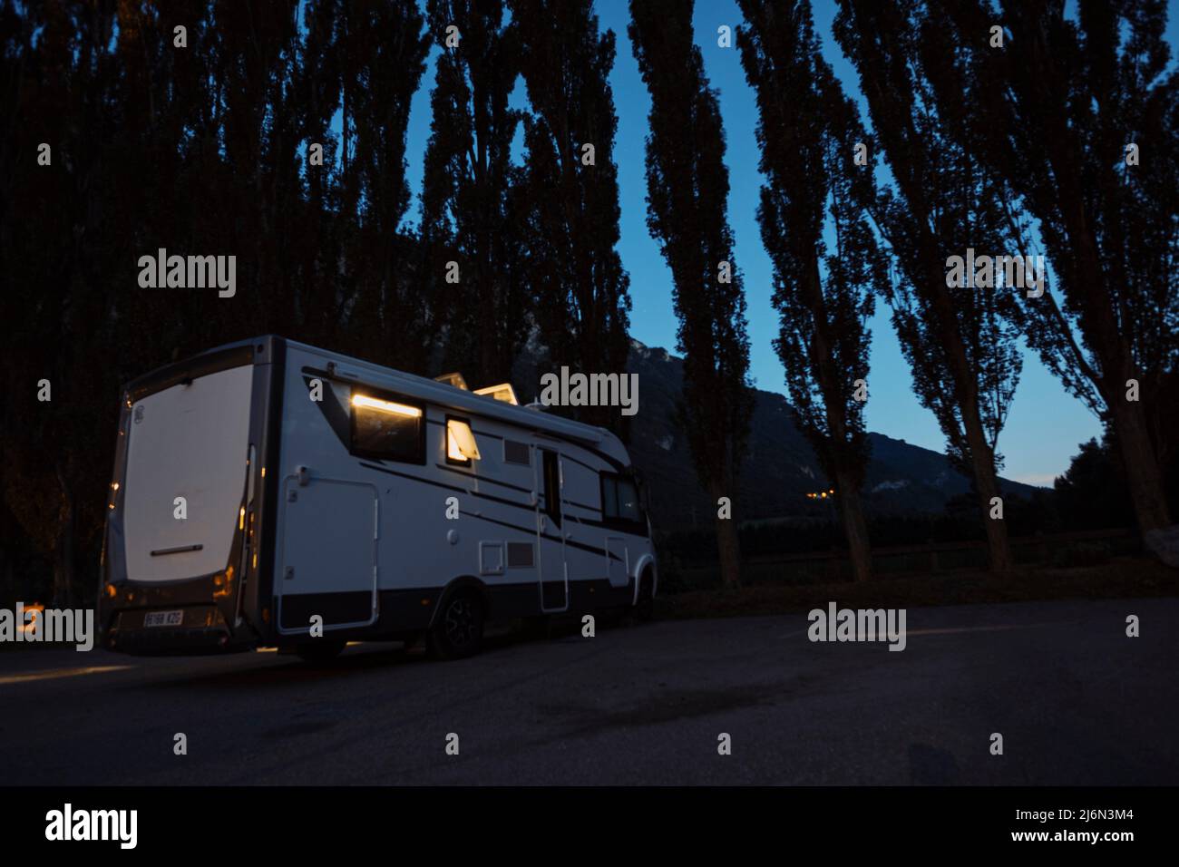 Vehículo autocaravana para transporte y vacaciones personas estacionadas por la noche cerca de un bosque disfrutando al aire libre en el estilo de vida de viaje. Foto de stock
