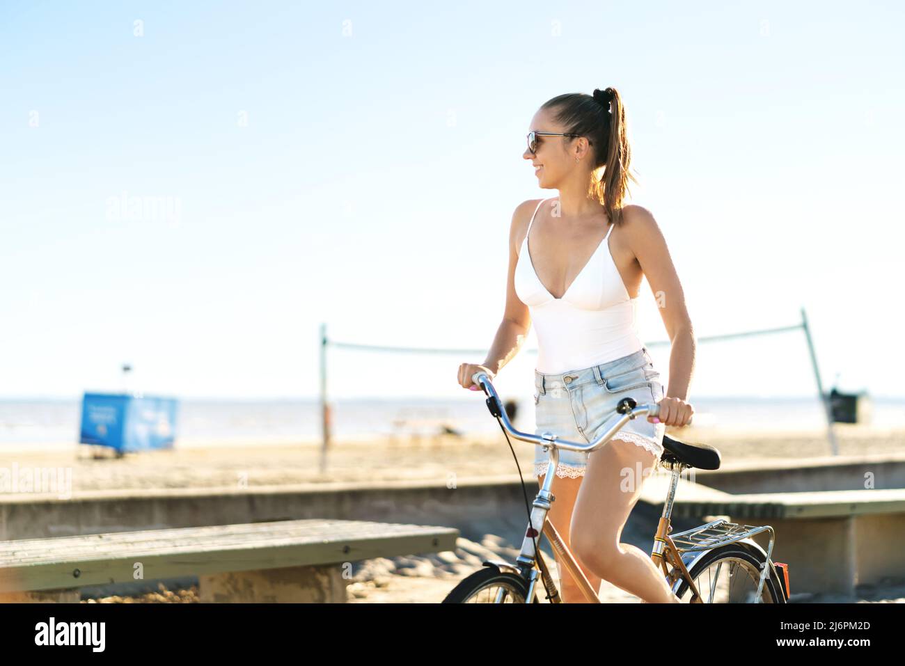 Bicicleta y la playa. Mujer en bicicleta en un paseo marítimo con una bicicleta retro vintage. Bonita ciclista femenina disfrutando de una sensación de verano feliz. Foto de stock