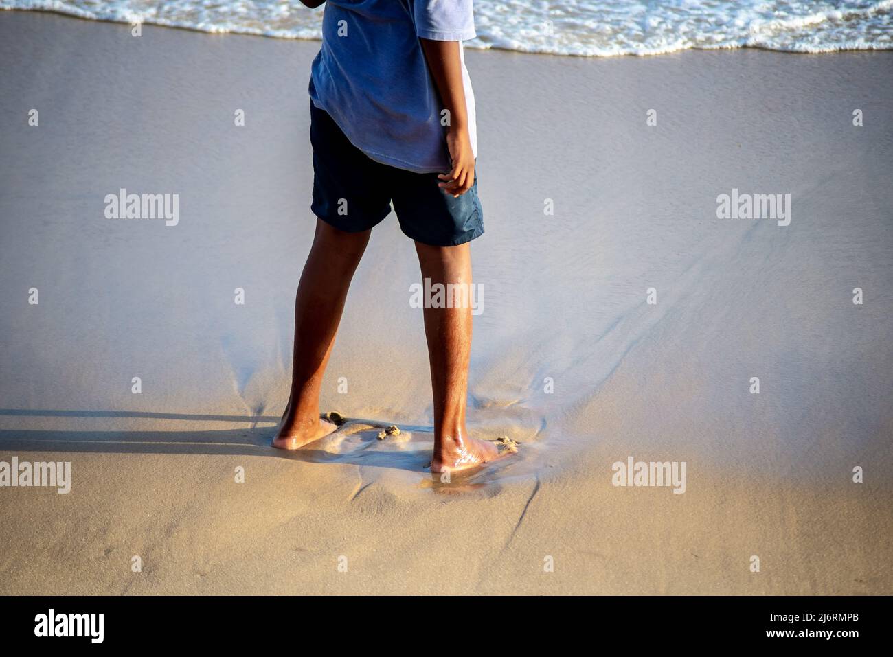 Parte inferior de una persona de pie sobre la arena de la playa. Ciudad de Salvador, estado de Bahia, Brasil. Foto de stock