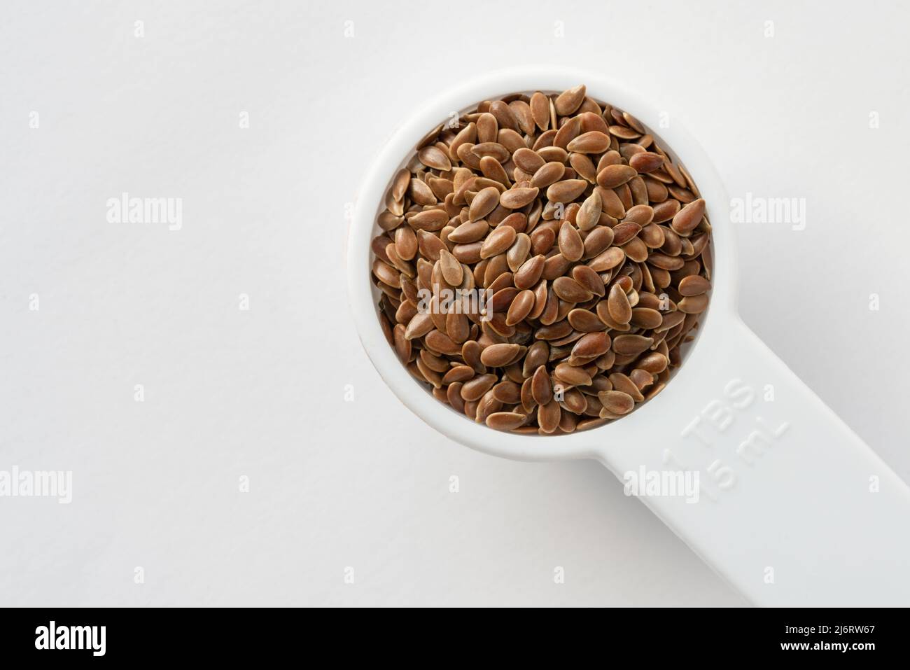 Dorar las semillas de lino en una cucharadita Foto de stock