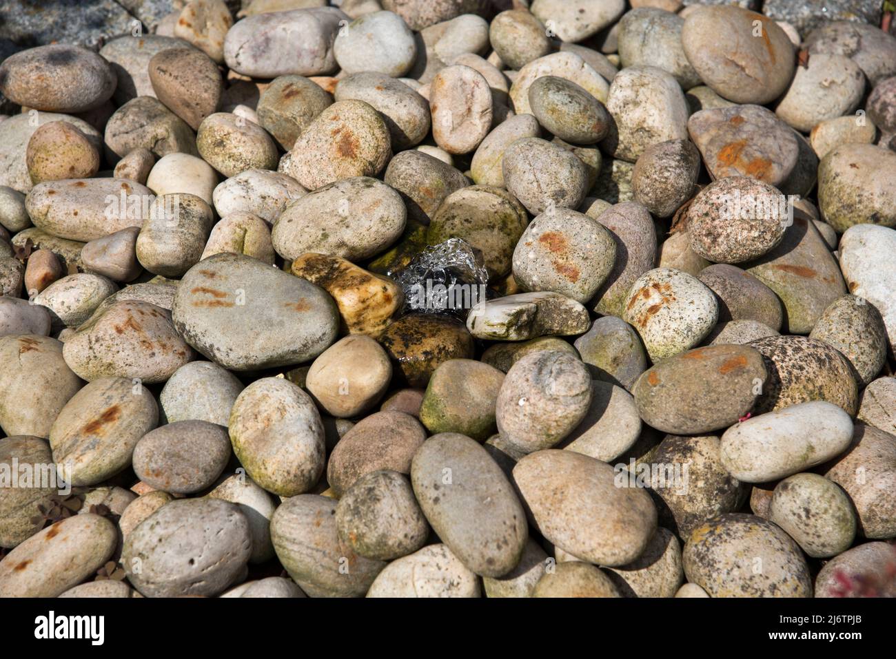 Piedras aleatorias que crean una característica de agua de guijarros Foto de stock