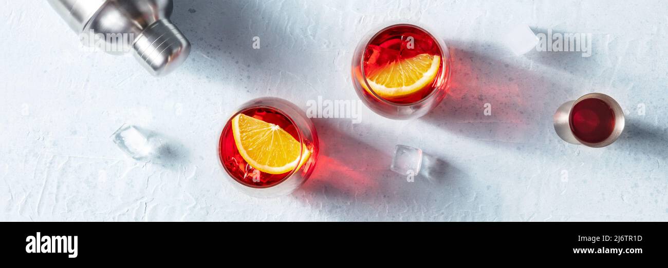 Cóctel Campari con naranjas frescas, un jigger y un coctelero, vista panorámica sobre el techo, pancarta panorámica de la fiesta de verano Foto de stock