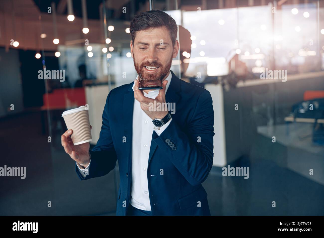 Atractivo hombre de negocios que utiliza un smartphone para grabar un mensaje de voz al socio empresarial Foto de stock