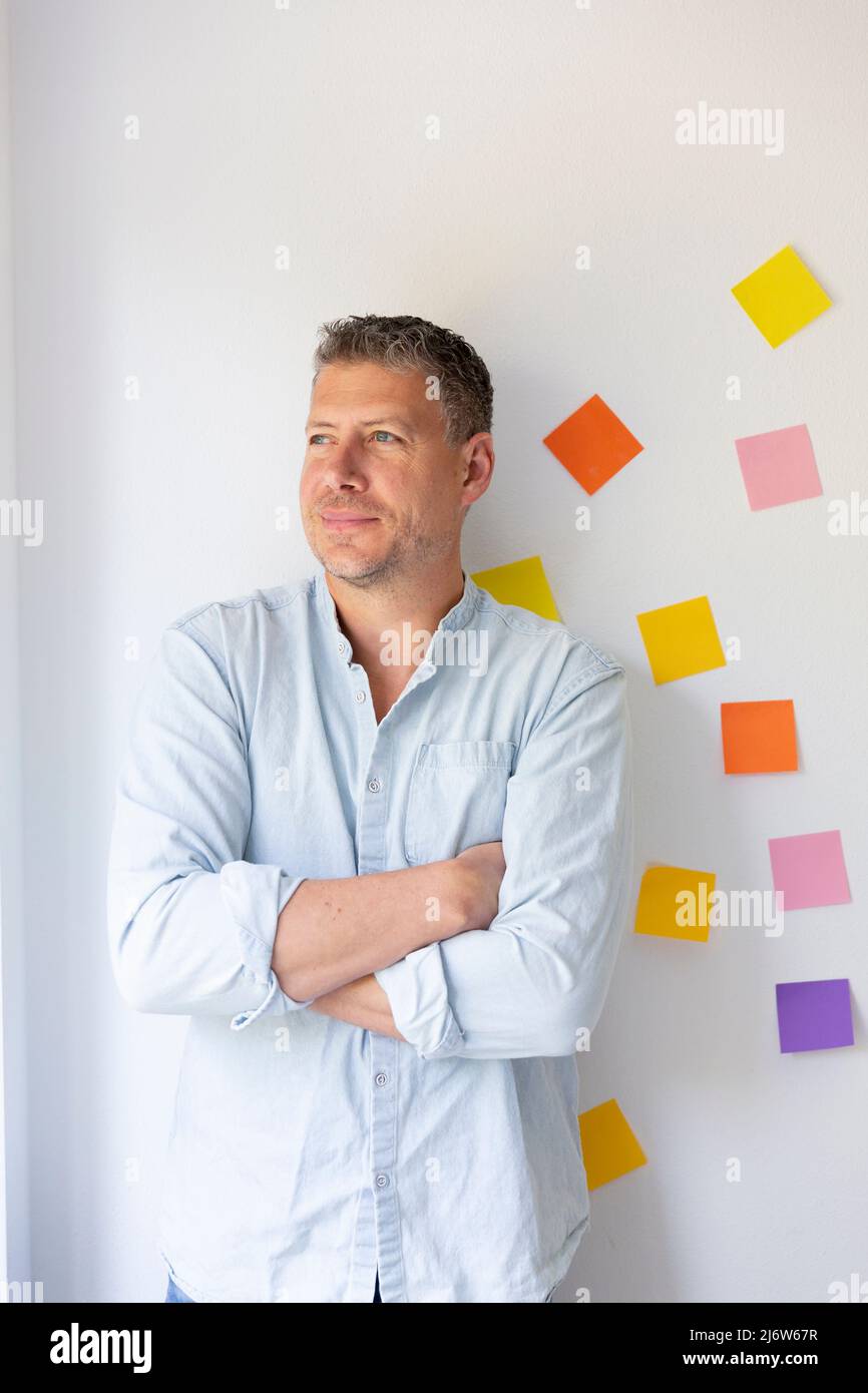 Retrato de hombre de negocios con camisa azul frente a una pared brillante  en la que se pegan muchas notas adhesivas de colores Fotografía de stock -  Alamy