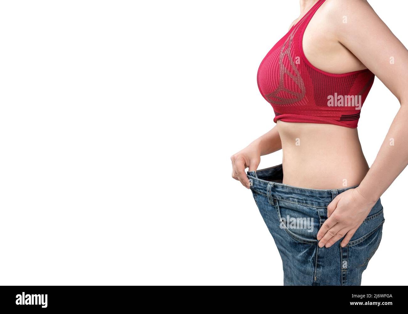 mujer con jeans demasiado grandes. Mujer con jeans sueltos. La mujer está midiendo la cintura después de la pérdida de peso. Aprobación de la dieta con vaqueros viejos demasiado grandes. D Foto de stock