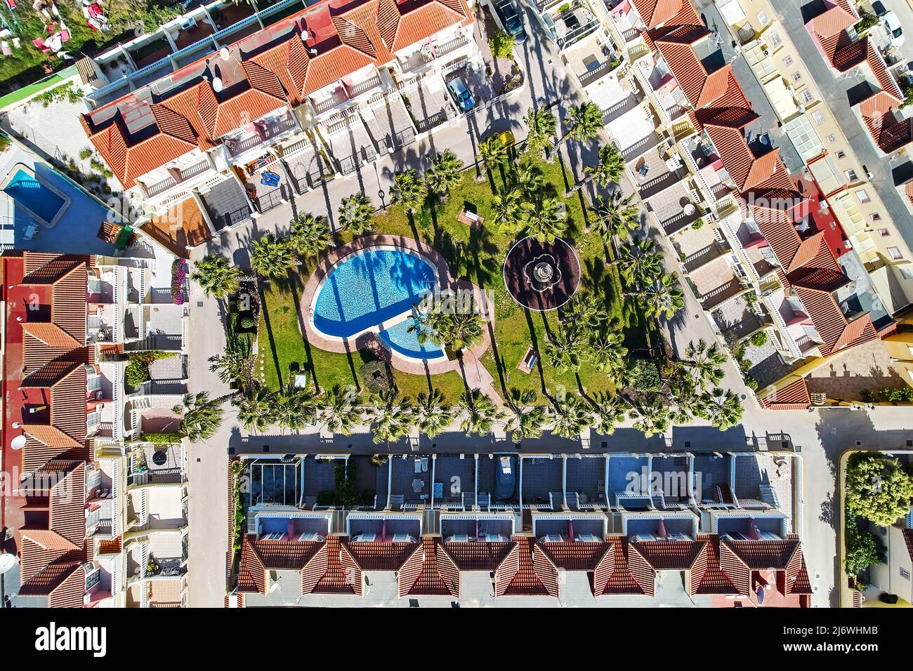 Vista aérea desde los tejados de la moderna urbanización con jardín interior bien cuidado, palmeras y piscina, no hay gente. Vacaciones de verano Foto de stock