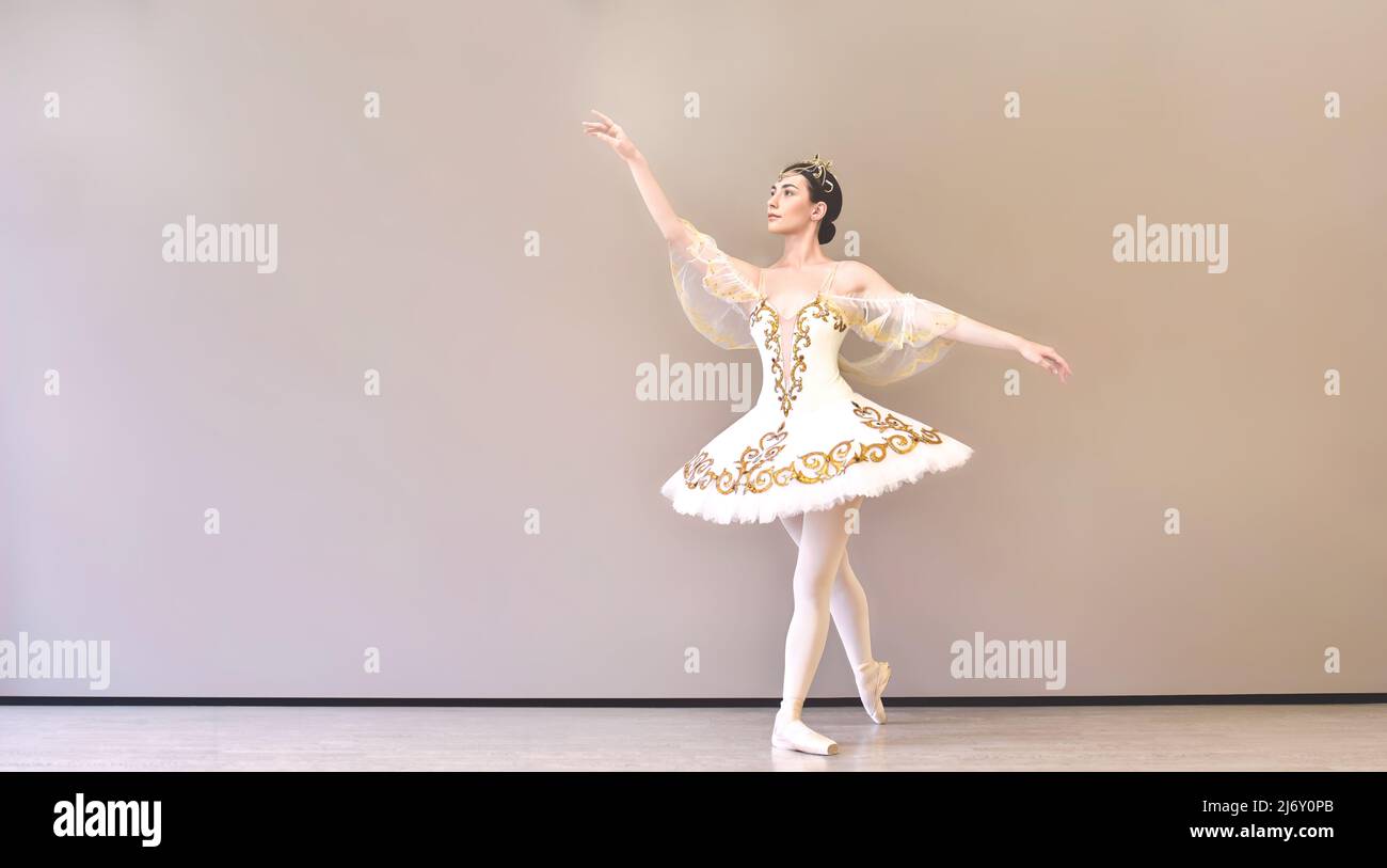 bailarina de ballet joven hermosa mujer en un tutu blanco que practica pasos de danza clásica en el estudio antes de la actuación Foto de stock