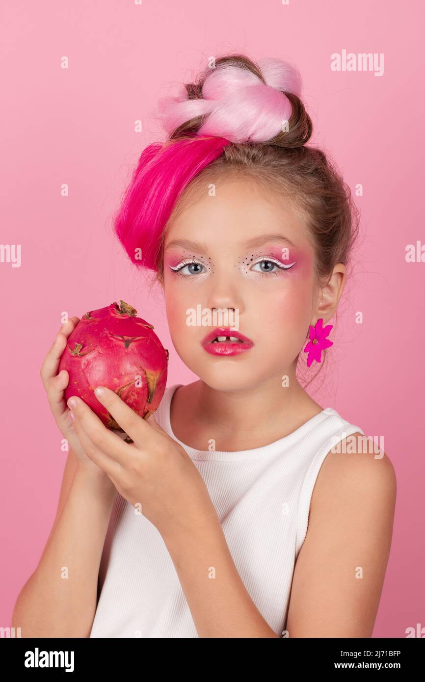 Primer plano retrato de chica bonita con peinado rosa con fruta de dragón  sobre fondo rosa. Estudio grabado de encantadora niña de tween con rosa  componen enjoyi Fotografía de stock - Alamy