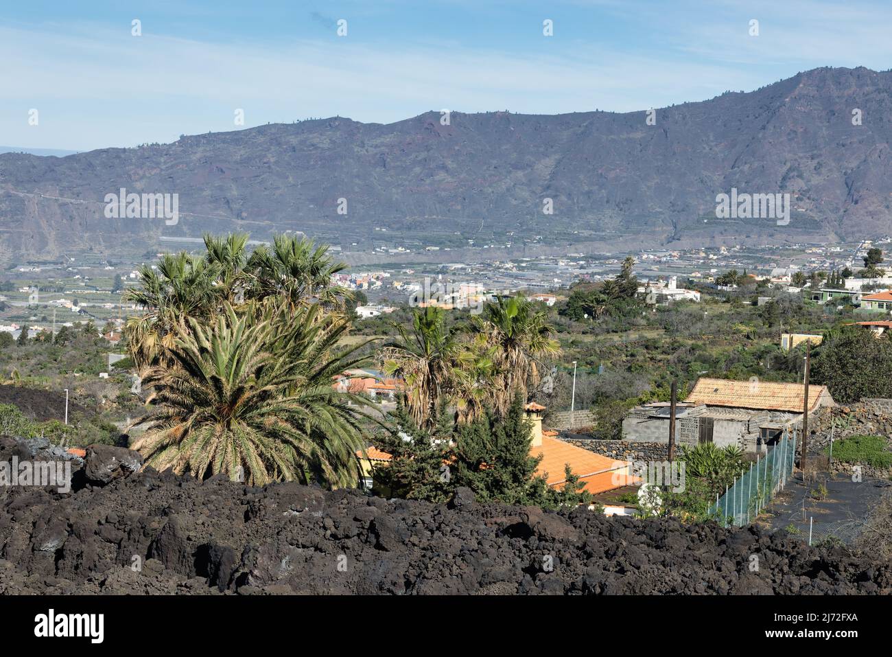 Casas y palmeras cerca de nuevo campo de lava del volcán recientemente erupcionado Cumbre Vieja en la Palma Foto de stock
