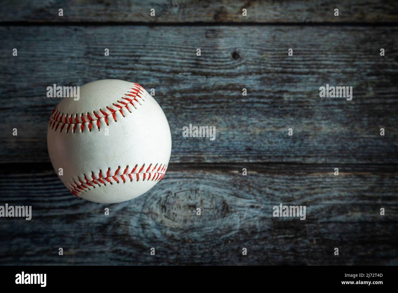 Pelota de béisbol o sóftbol de cuero sobre fondo rústico de madera con espacio de copia. Foto de stock