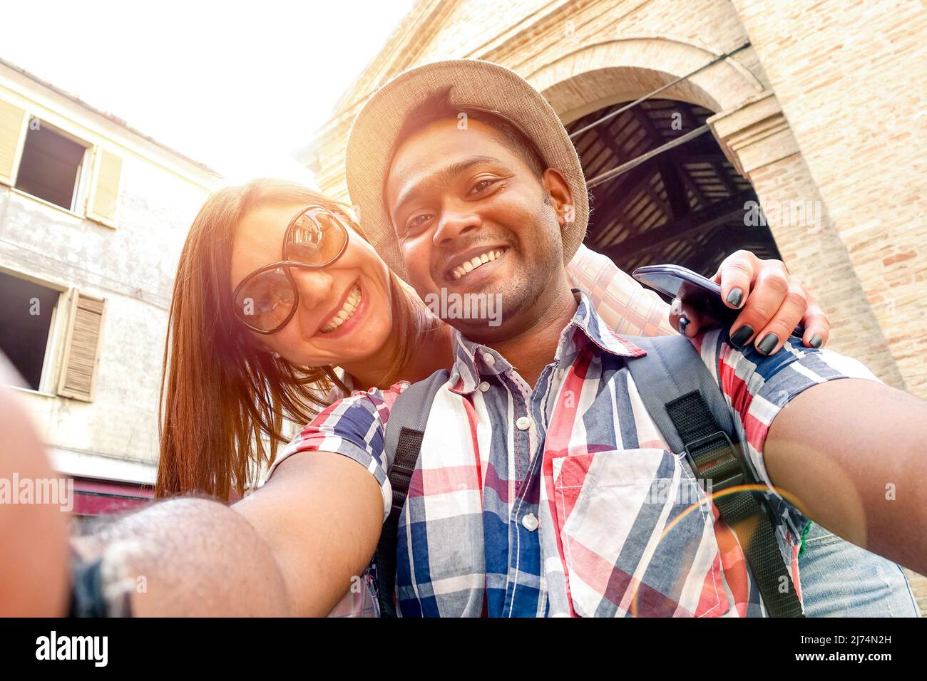 Pareja multirracial tomando selfie en el viaje de la vieja ciudad - Concepto divertido con viajeros de moda alternativa - novio indio con novia caucásica - cálido Foto de stock