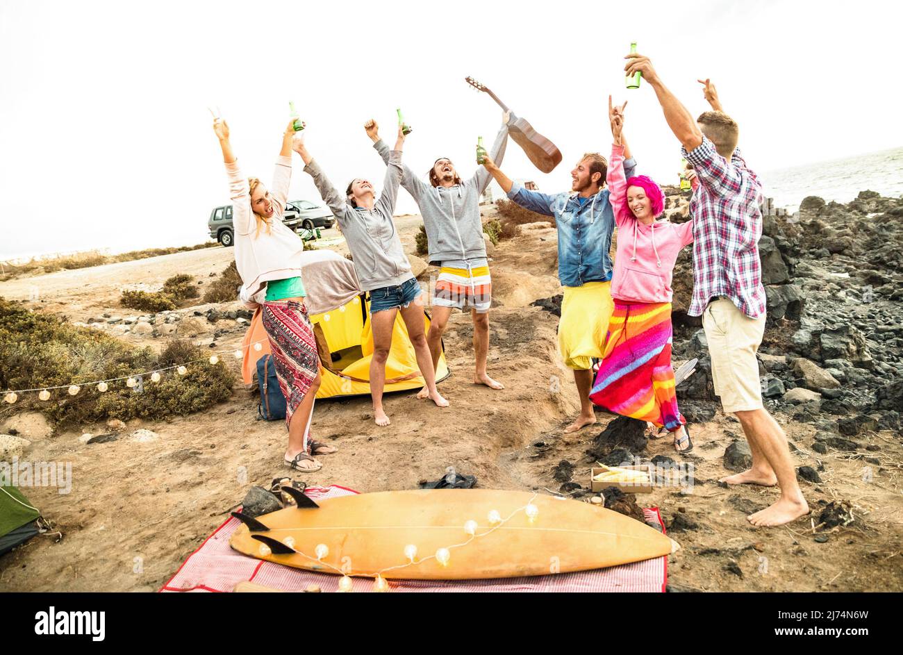 Amigos hippie divertirse juntos en la playa camping fiesta de música - concepto de viajes de amistad con los jóvenes vagadores bailando y bebiendo cerveza en s Foto de stock