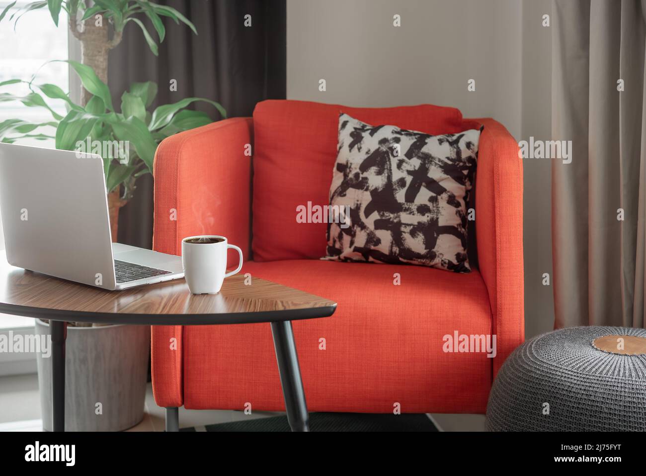 Lugar de trabajo en casa con un ordenador portátil y una taza de café en una mesa de café. Foto de stock