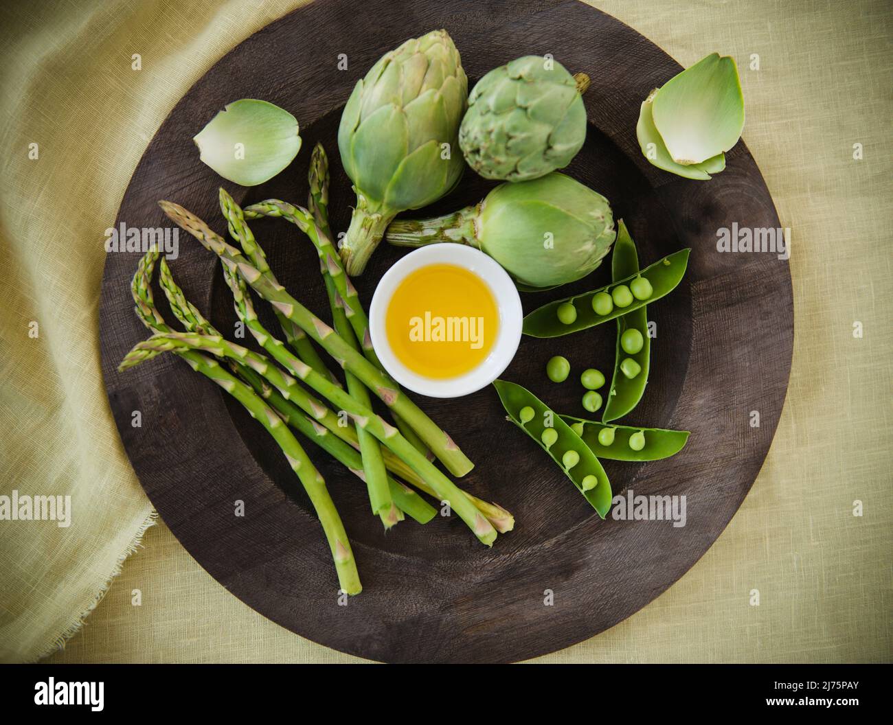 Verduras verdes mezcladas con aceite de oliva; espárragos, alcachofas y guisantes Foto de stock