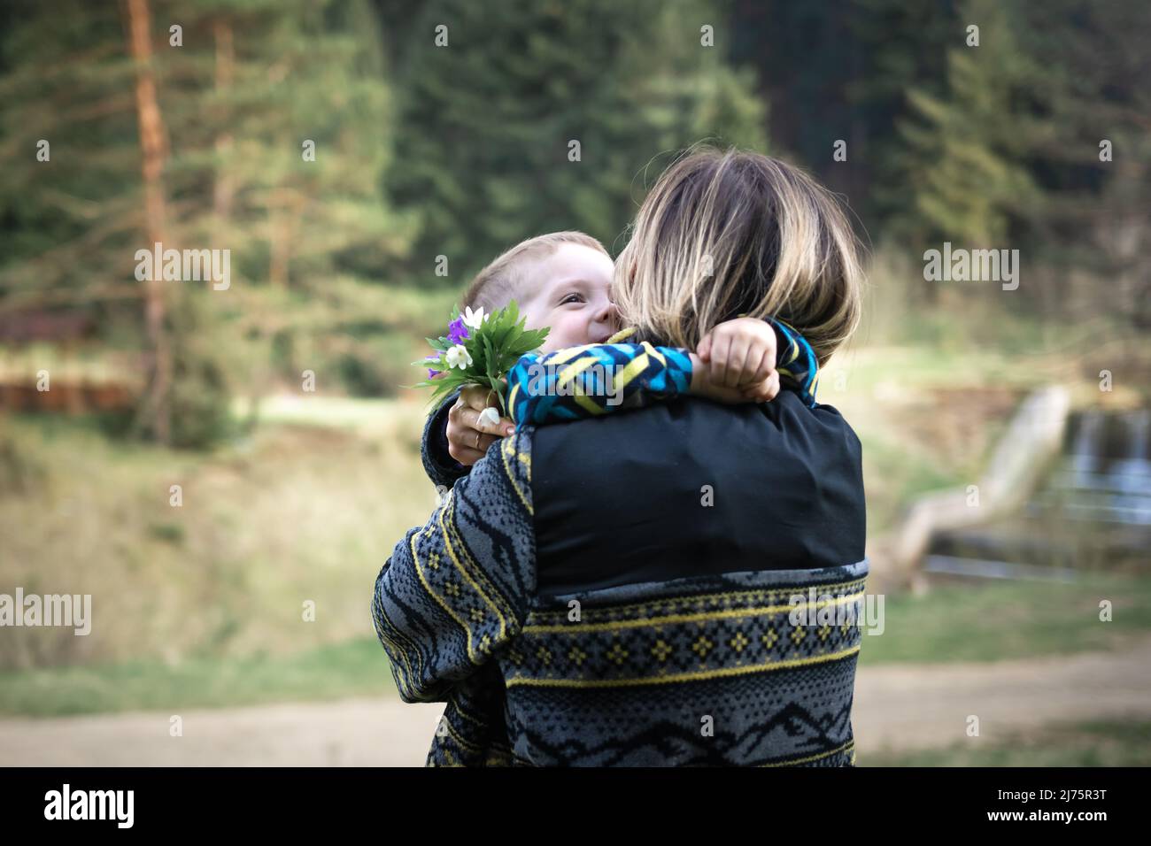 Mamá abraza a su hijo después de un regalo de un ramo de flores de él Foto de stock