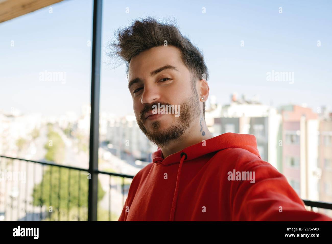 Posando, hombre joven haciendo selfie, hombre adulto con barba vestido de  sudadera roja Fotografía de stock - Alamy
