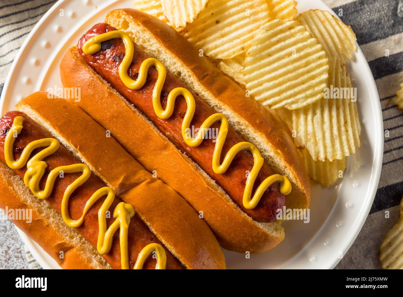 Perro caliente americano casero con patatas fritas y mostaza Foto de stock