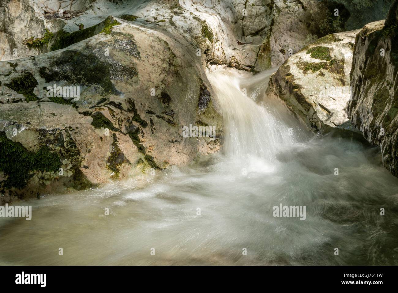 Pequeño arroyo en Kesselberg cerca de Kochel entre rocas en la luz con musgo en piedra. Foto de stock