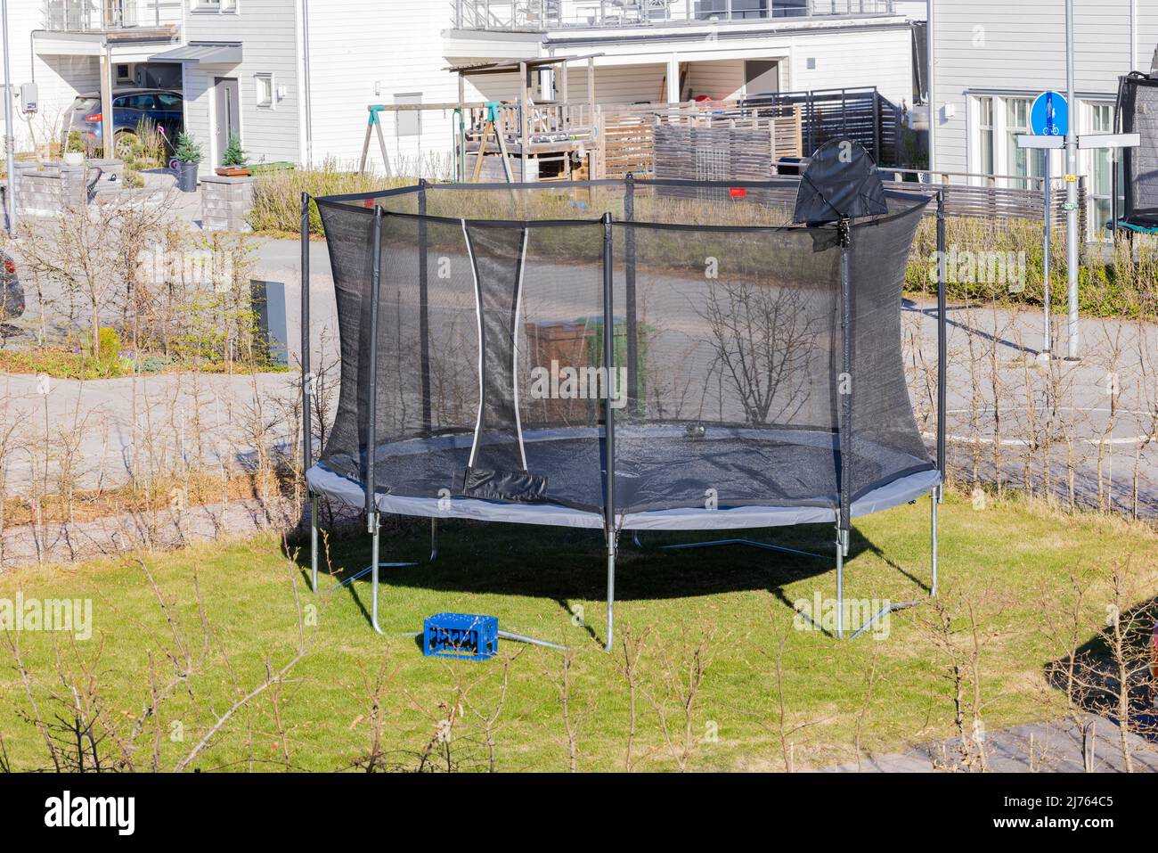 Hermosa vista del trampolín con red protectora instalada en el patio. Concepto de recreación activa. SUECIA. Foto de stock