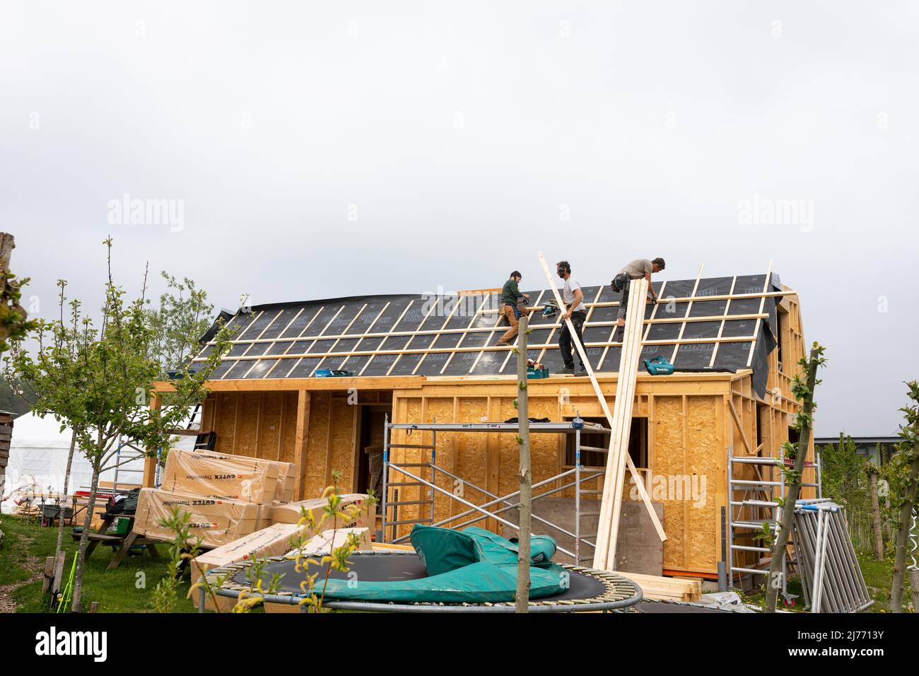 Trabajadores en el techo construyendo una casa ecológica en el pueblo ecológico Oosterwold, Almere, Países Bajos Foto de stock